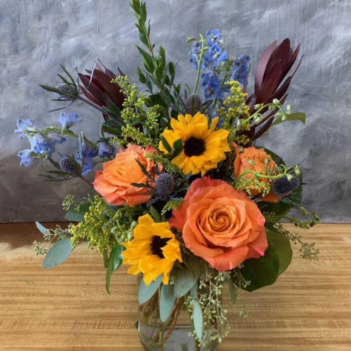 Bouquet of orange roses and yellow sunflowers in a glass vase