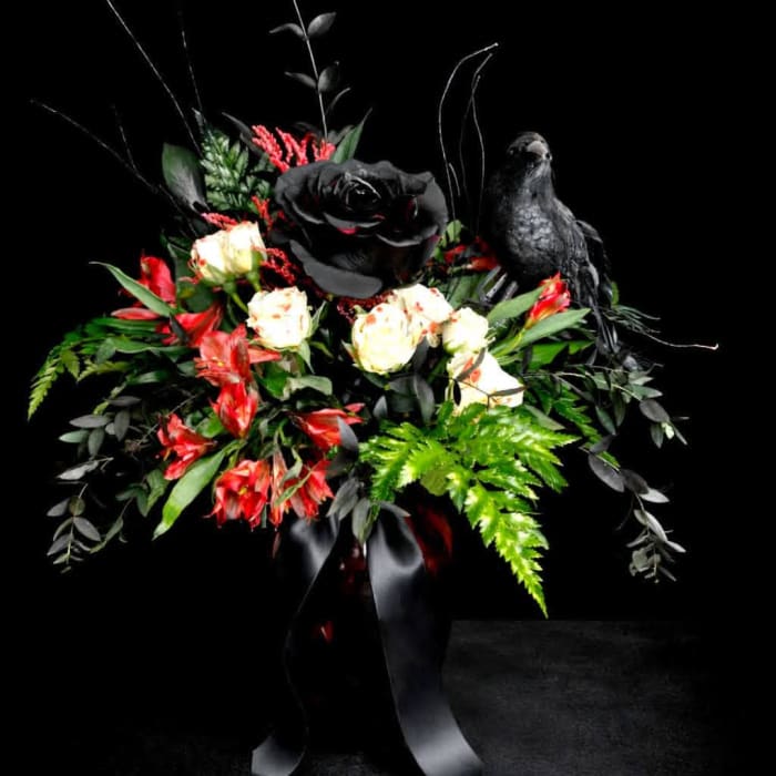 Black and red floral arrangement with a black bird figurine