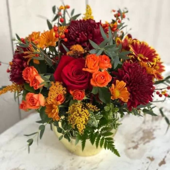 Bouquet of red and orange flowers in a pale vase
