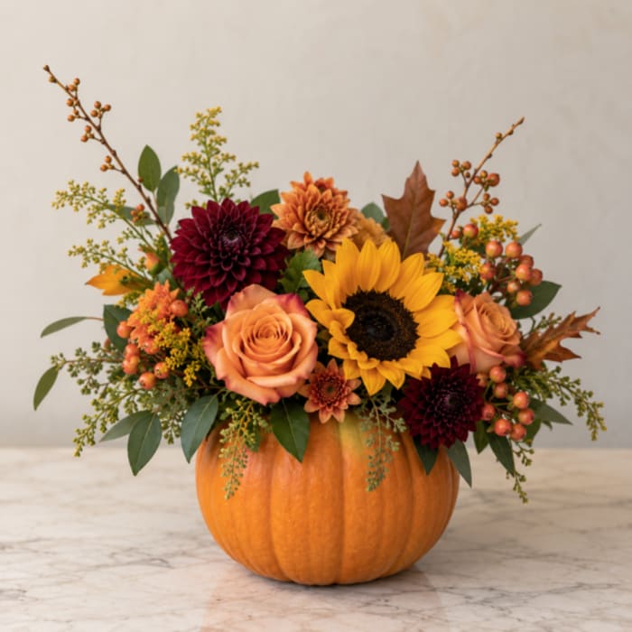 Fall floral arrangement in a pumpkin with sunflowers, roses, and dahlias