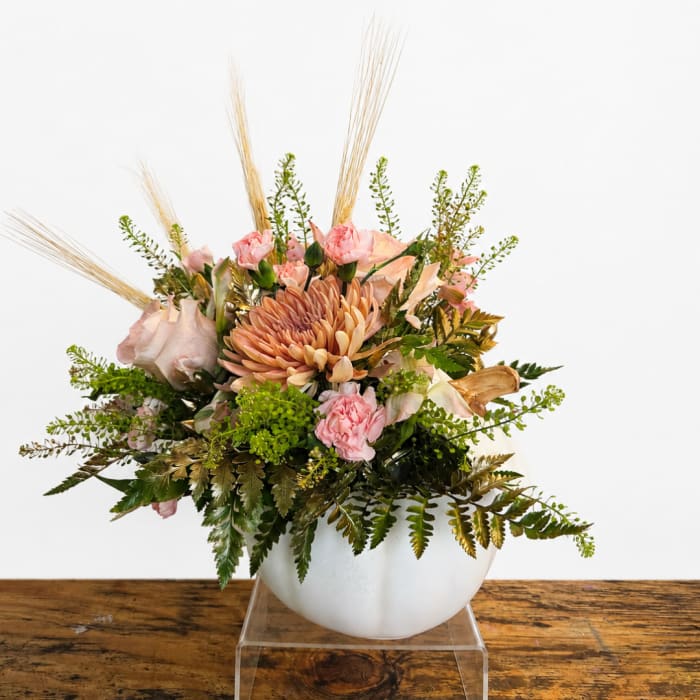 Pink and peach floral arrangement in a white bowl vase
