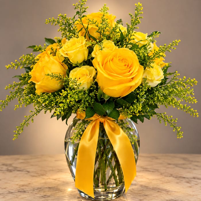 Yellow roses in a clear glass vase with a yellow ribbon