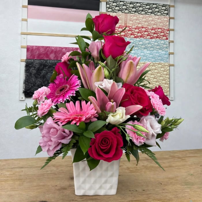 Pink and red mixed flower arrangement in a white vase
