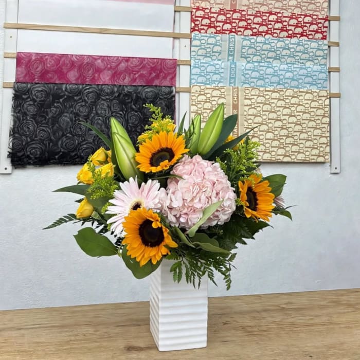 Sunflower and hydrangea arrangement in a white vase