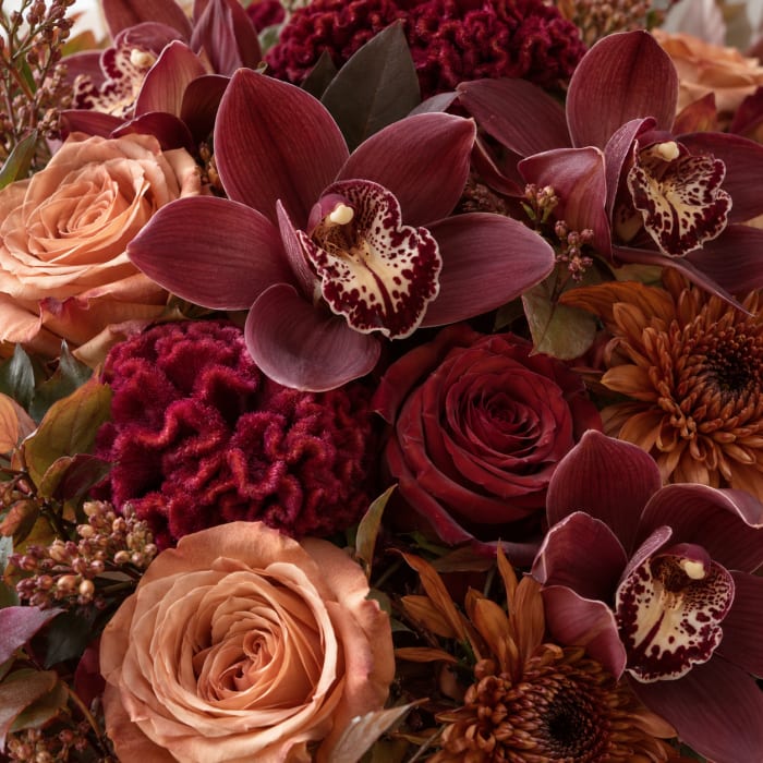 Bouquet of burgundy orchids, peach roses, and orange chrysanthemums