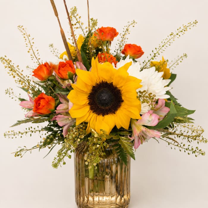 Sunflower and mixed rose bouquet in a ribbed glass vase