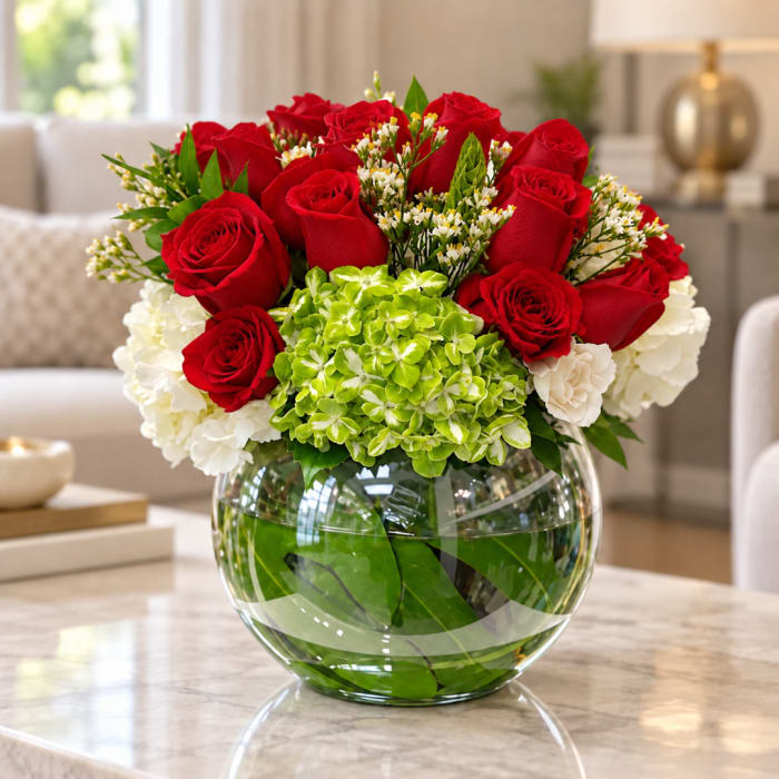 Red roses and white flowers arranged in a round glass vase