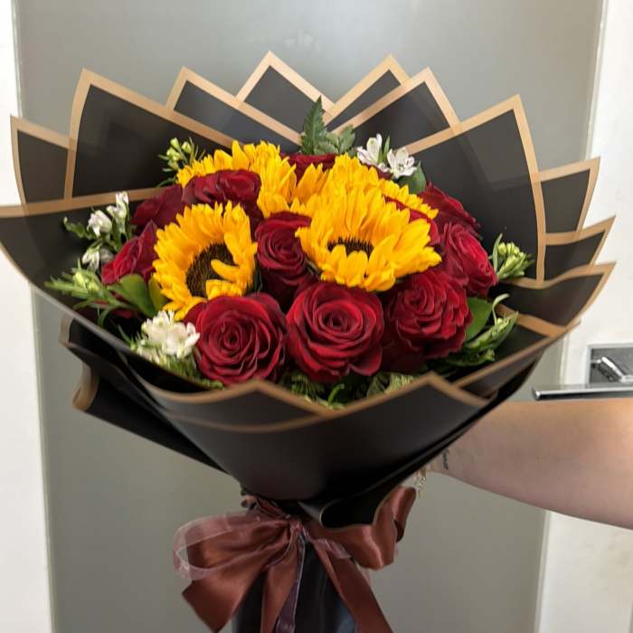 Bouquet of red roses and yellow sunflowers wrapped in black paper