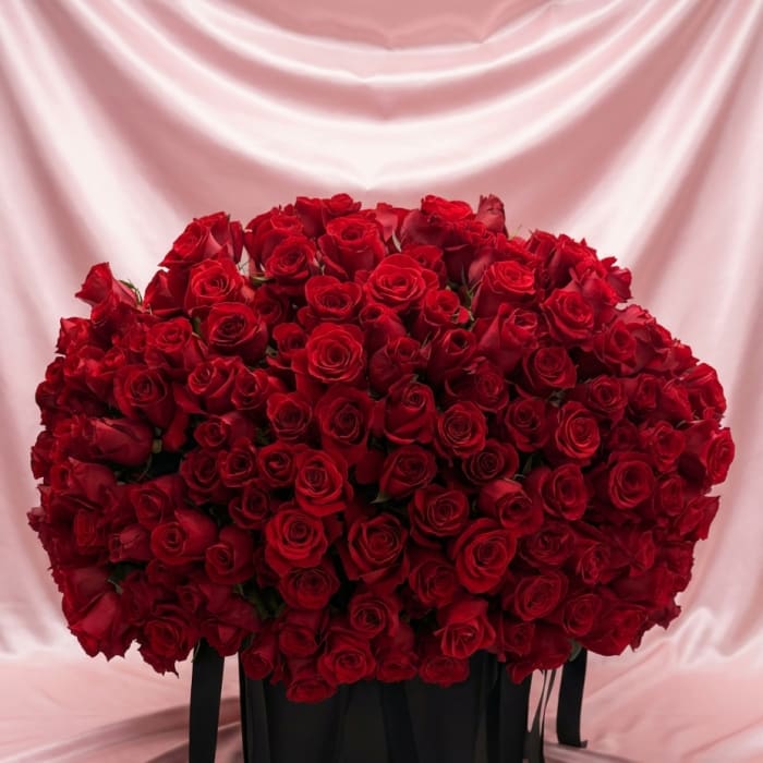 Large bouquet of red roses in a black box with ribbon tails