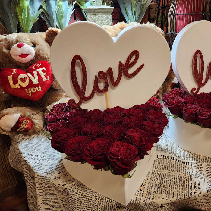 Heart-shaped rose arrangements with "love" signs and teddy bears