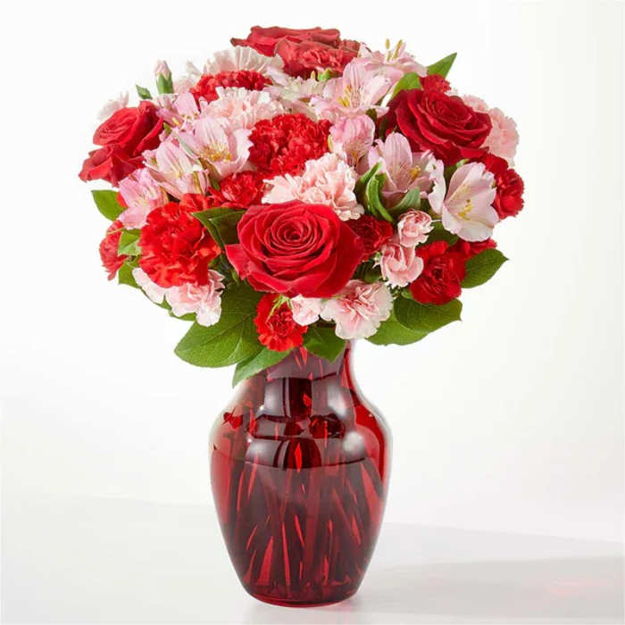 Red roses and pink carnations in a red glass vase