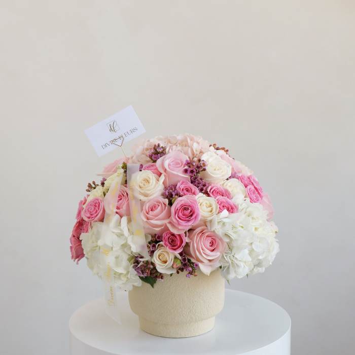 Pink and white rose bouquet in a cream vase