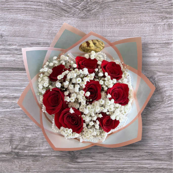 Bouquet of red roses and white baby's breath wrapped in translucent paper