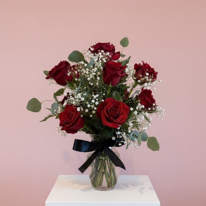 Bouquet of red roses in a glass vase with a black ribbon