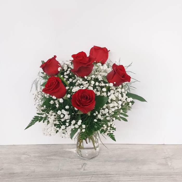 Arrangement of red roses and white baby's breath in a clear glass vase