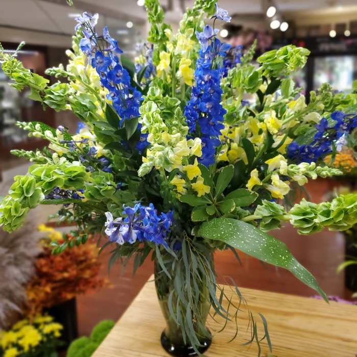 Tall bouquet of blue and yellow flowers in a glass vase