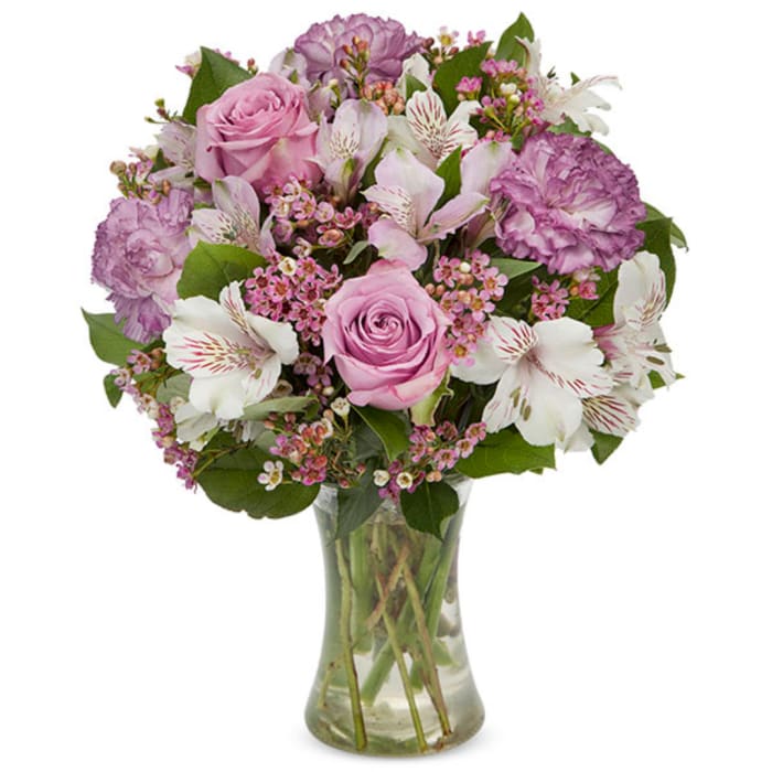 Pink roses and purple flowers arranged in a clear glass vase