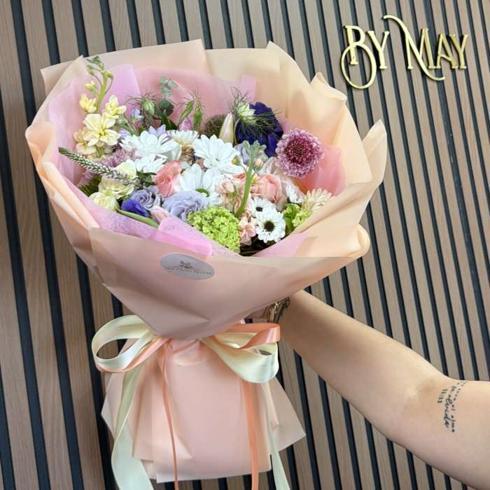 Pastel mixed flower bouquet wrapped in pink paper with ribbon