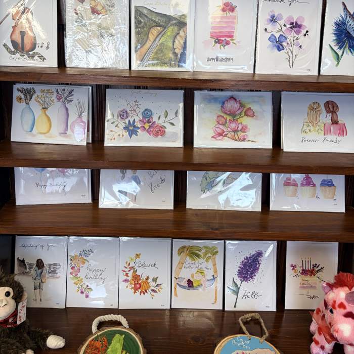 Display shelf of watercolor greeting cards with floral designs and birthday messages
