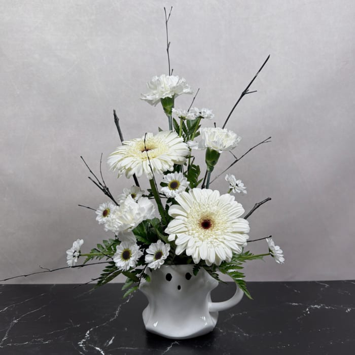White gerbera daisies and carnations arranged in a white ceramic vase