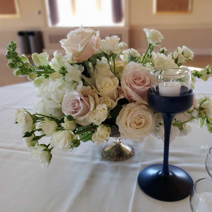 White and blush roses arranged with white blooms in a low centerpiece.