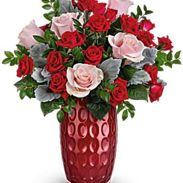Arrangement of red and pale pink roses in a tall textured red vase