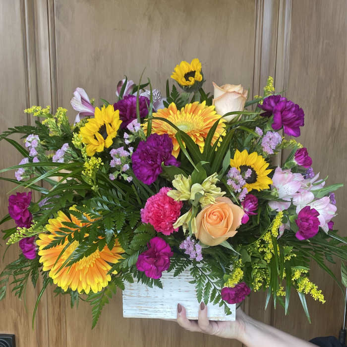 Colorful mixed bouquet in a white wooden box with sunflowers and roses