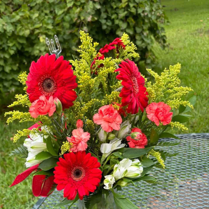 Red gerbera daisies and pink carnations in a glass vase
