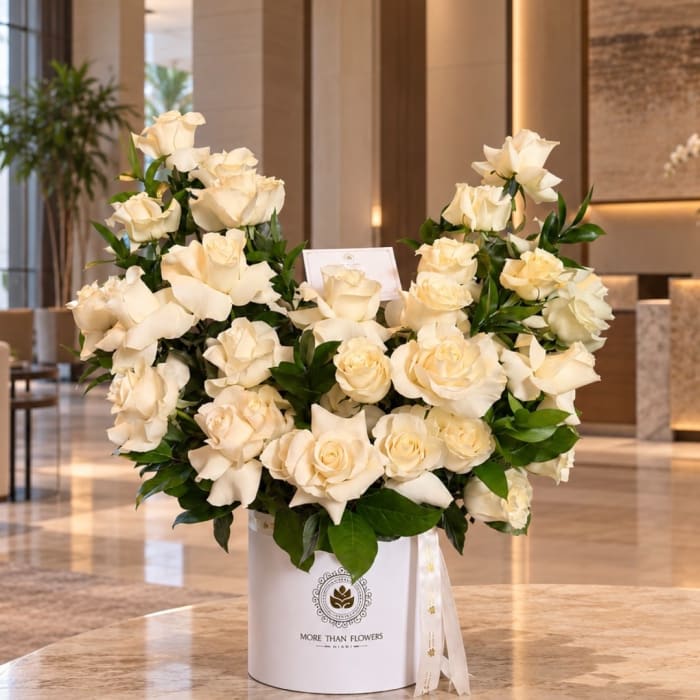 Cream rose arrangement in a white hatbox with a ribbon