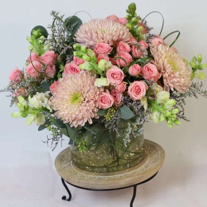Pink roses and pale chrysanthemums arranged in a glass vase