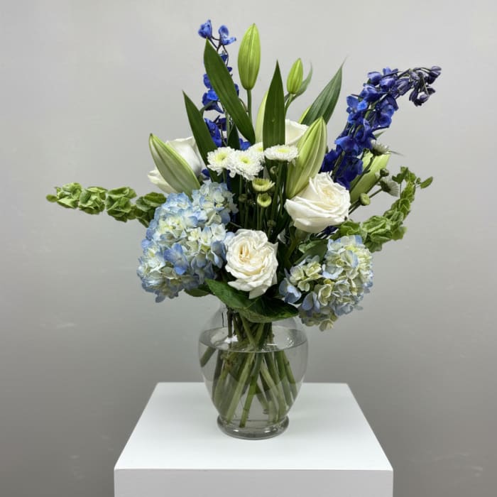 Blue and white floral arrangement in a clear glass vase