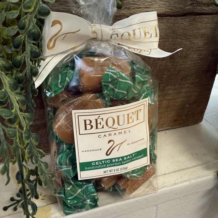 Bag of caramel candies tied with a ribbon beside faux greenery