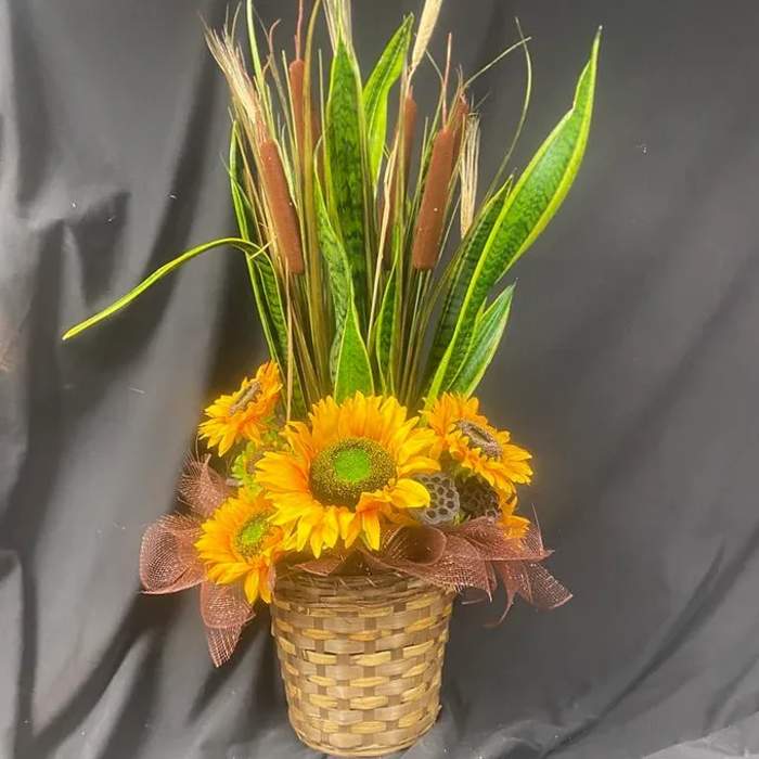Sunflower arrangement in a woven basket with tall cattails and grasses