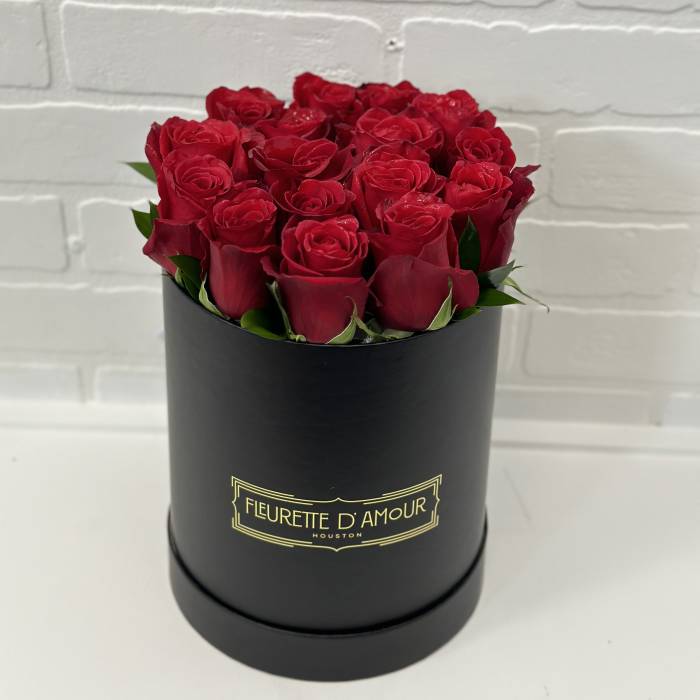 Red roses arranged in a black round box