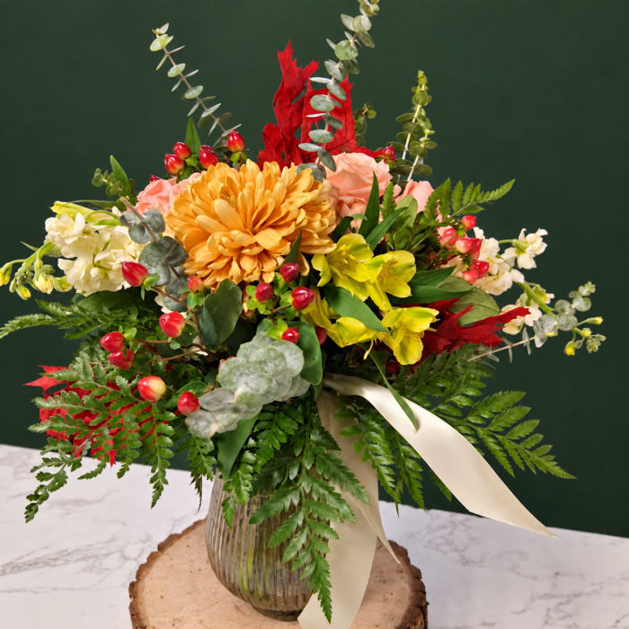 Mixed bouquet in a ribbed glass vase with a cream ribbon