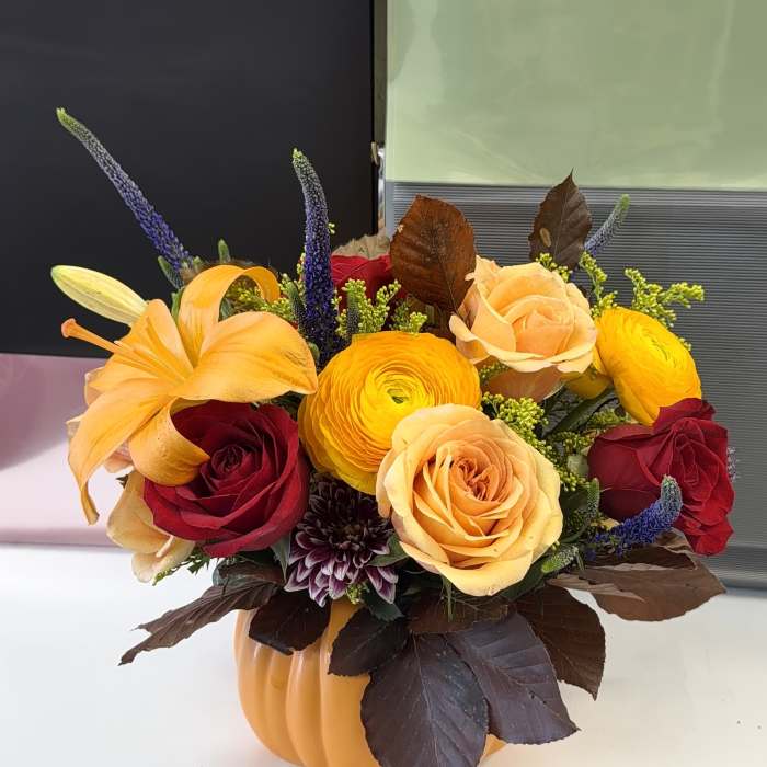 Autumn floral arrangement in a pumpkin container with roses and lilies