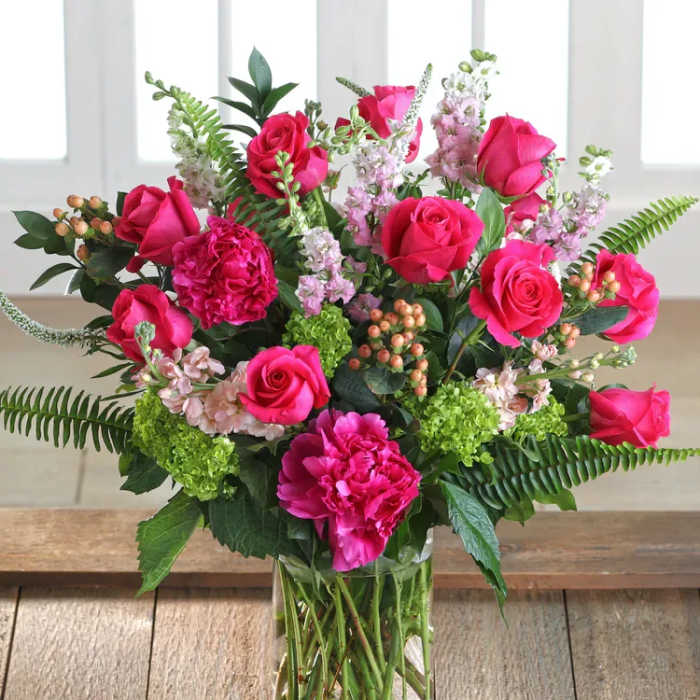 Pink roses and carnations arranged in a clear glass vase