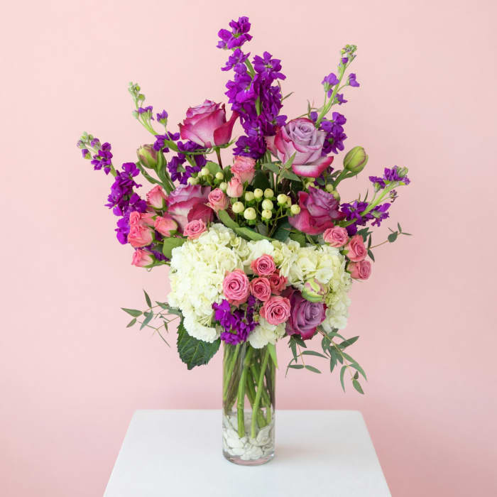 Pink and purple mixed flower arrangement in a clear glass vase