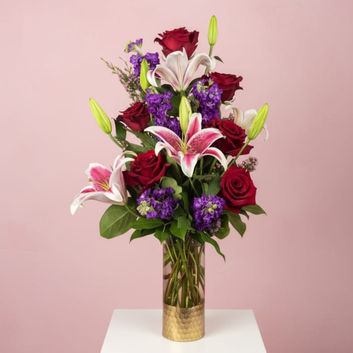 Red roses and pink lilies arranged in a tall glass vase