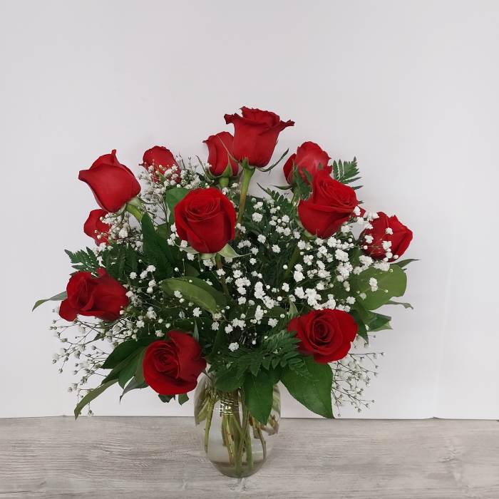 Arrangement of red roses with white filler flowers in a clear glass vase