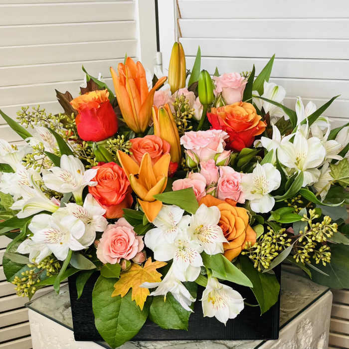Mixed bouquet of roses, lilies, and white alstroemeria in a black box