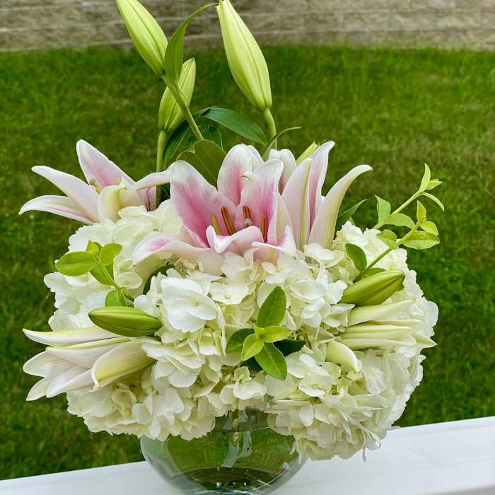 Pink lilies and white hydrangeas in a glass bowl vase