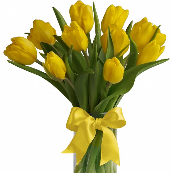 Bouquet of yellow tulips in a clear glass vase with a yellow ribbon bow