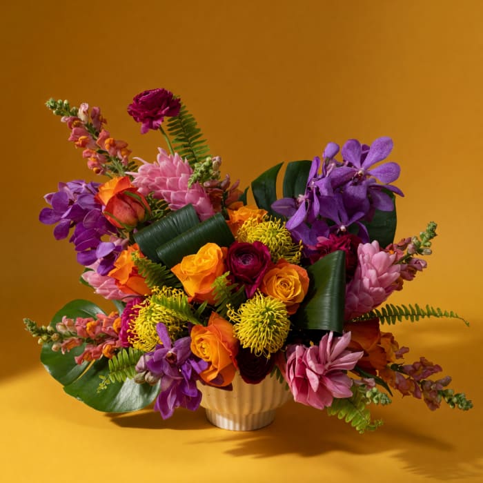 Colorful bouquet of roses, orchids, and mums in a white vase