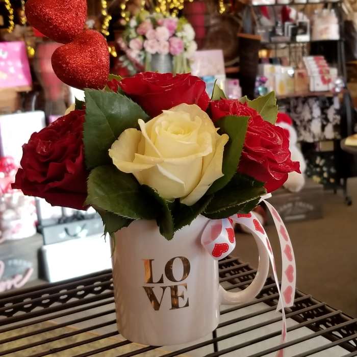 Red and cream roses in a white mug with heart ribbon