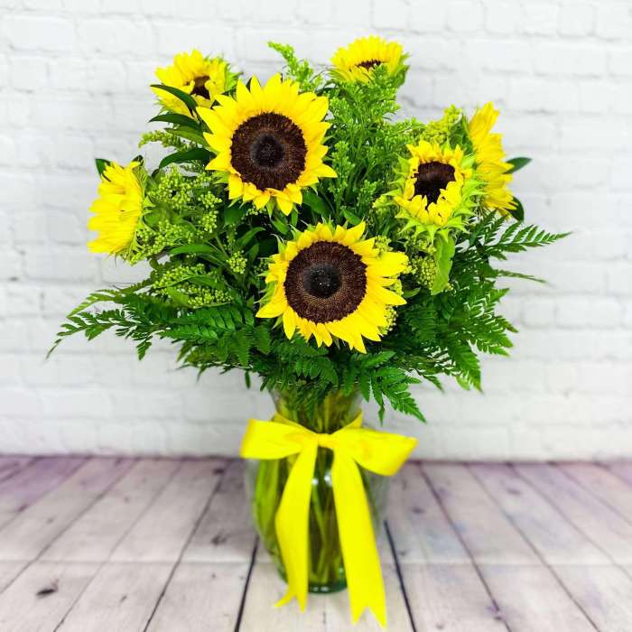 Sunflower bouquet in a glass vase with a yellow ribbon