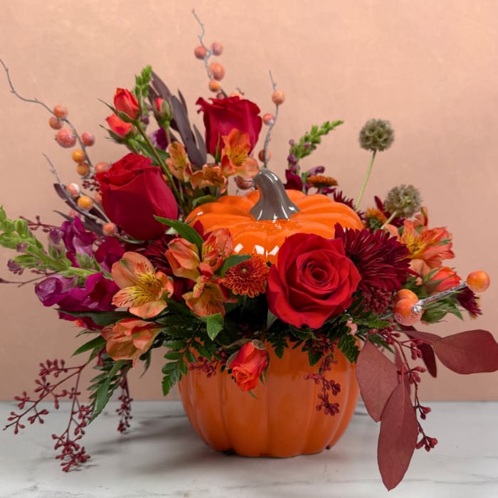 Pumpkin-shaped vase filled with red and orange flowers