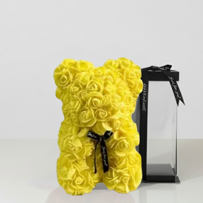 Yellow teddy bear made of roses beside a black gift box