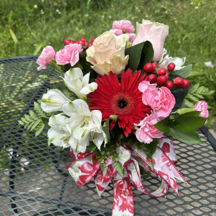 Bouquet of pink, white, and red flowers tied with a floral ribbon.