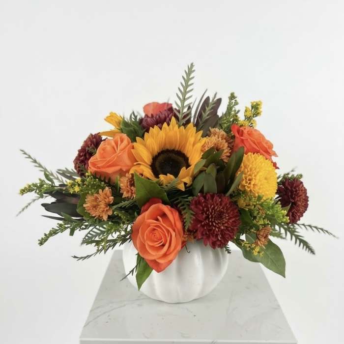 Orange and yellow mixed flower arrangement in a white vase